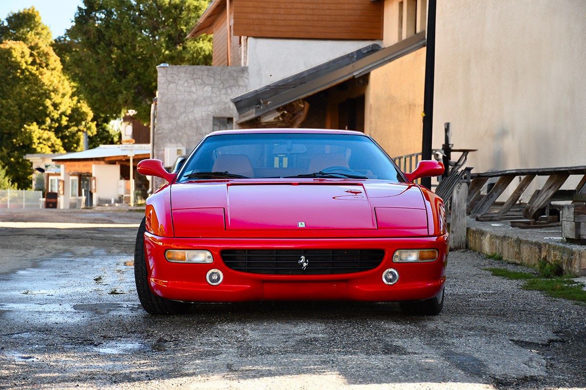 Ferrari F355 rouge devant une bâtisse en pierre