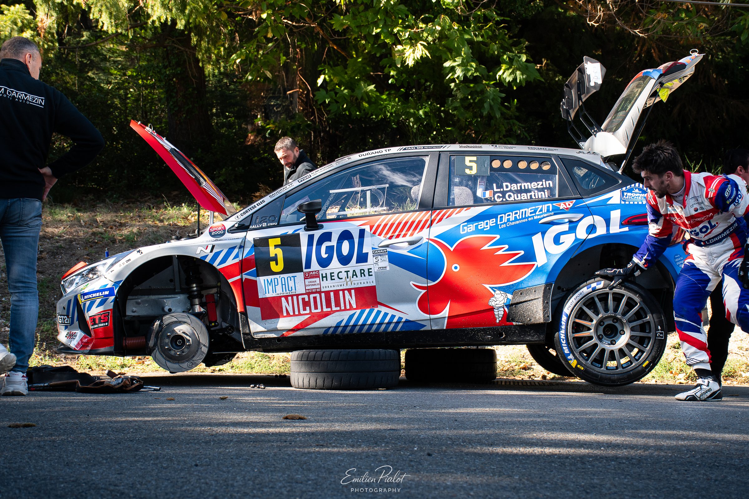 Voiture de rallye blanche phares allumés au milieu des feuilles mortes