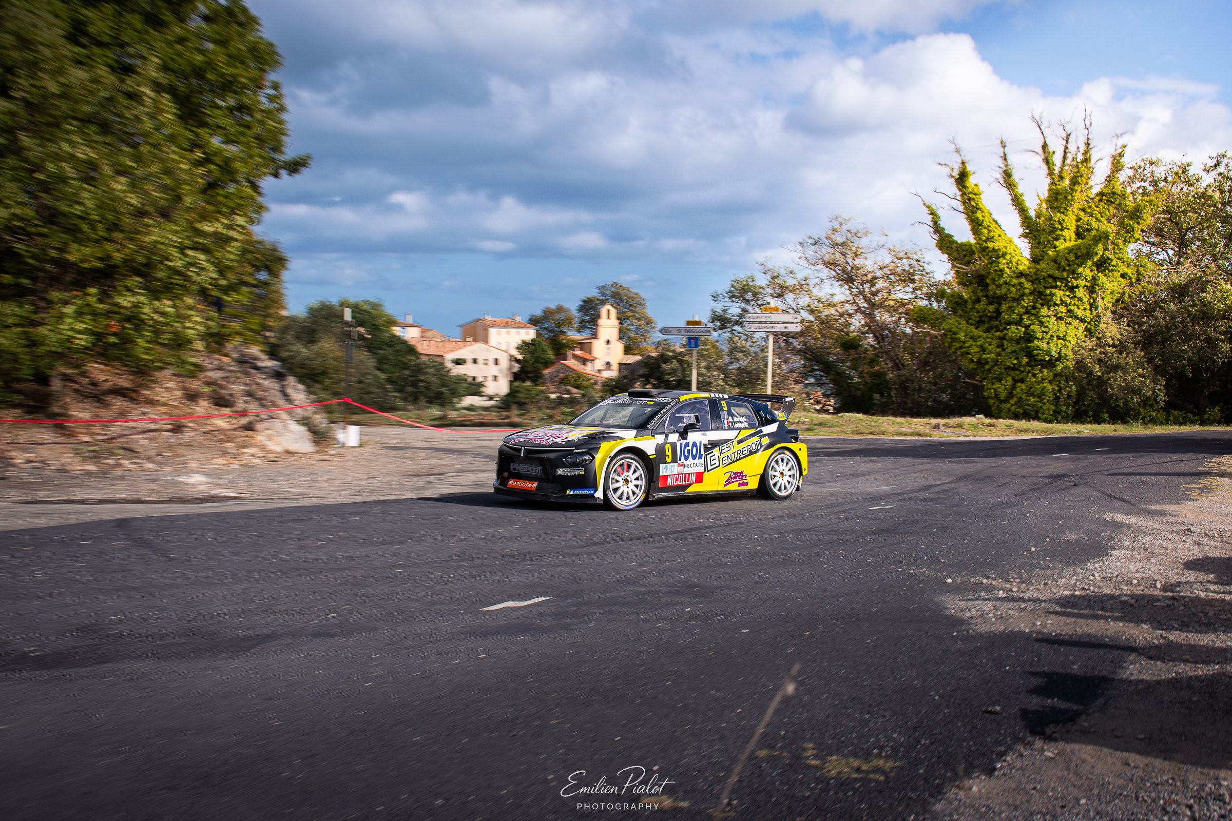 Citroën C3 Rally2 verte et grise IGOL négociant une épingle devant un village
