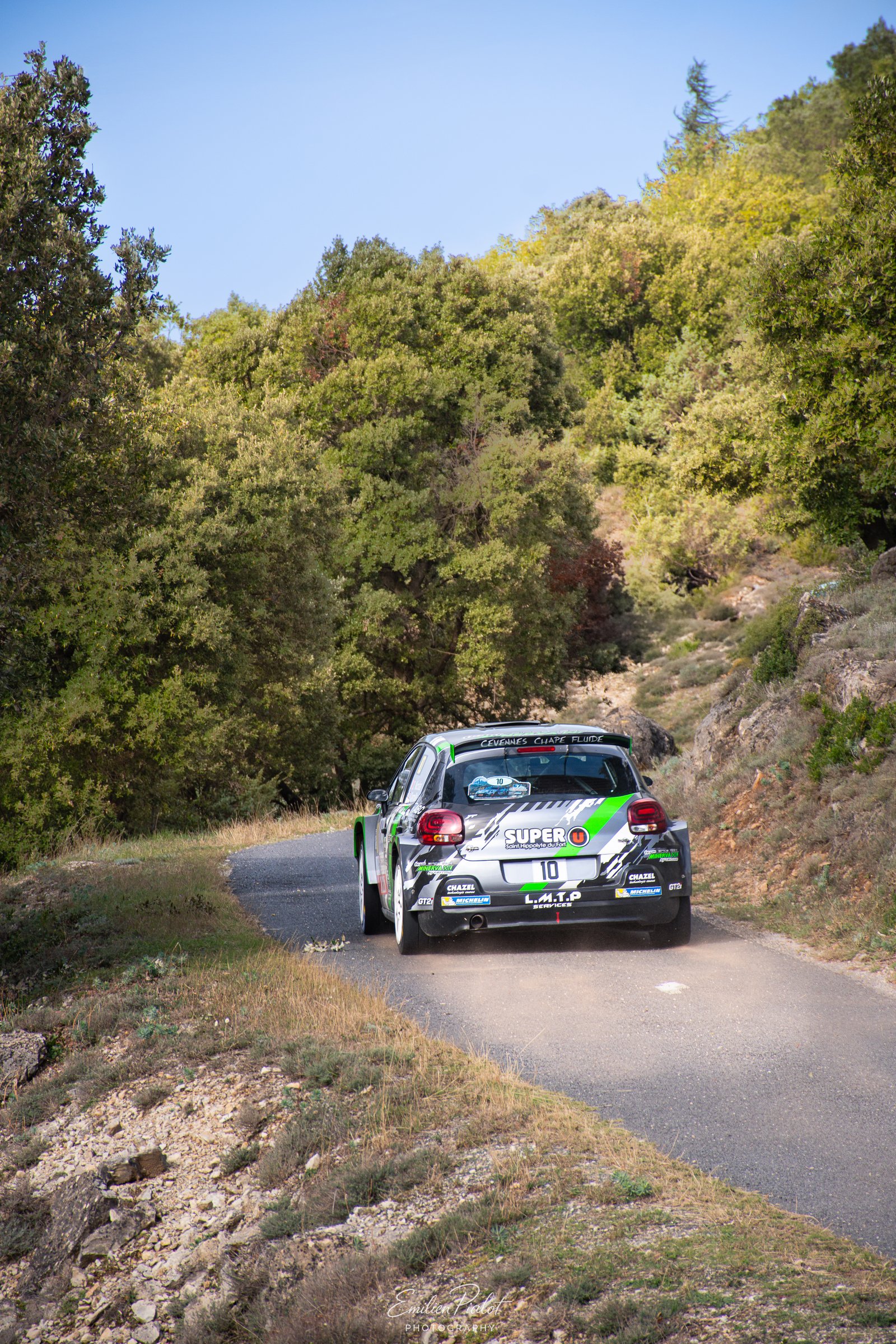 Peugeot 208 Rally4 verte et blanche dans une épingle encadrée par la roche