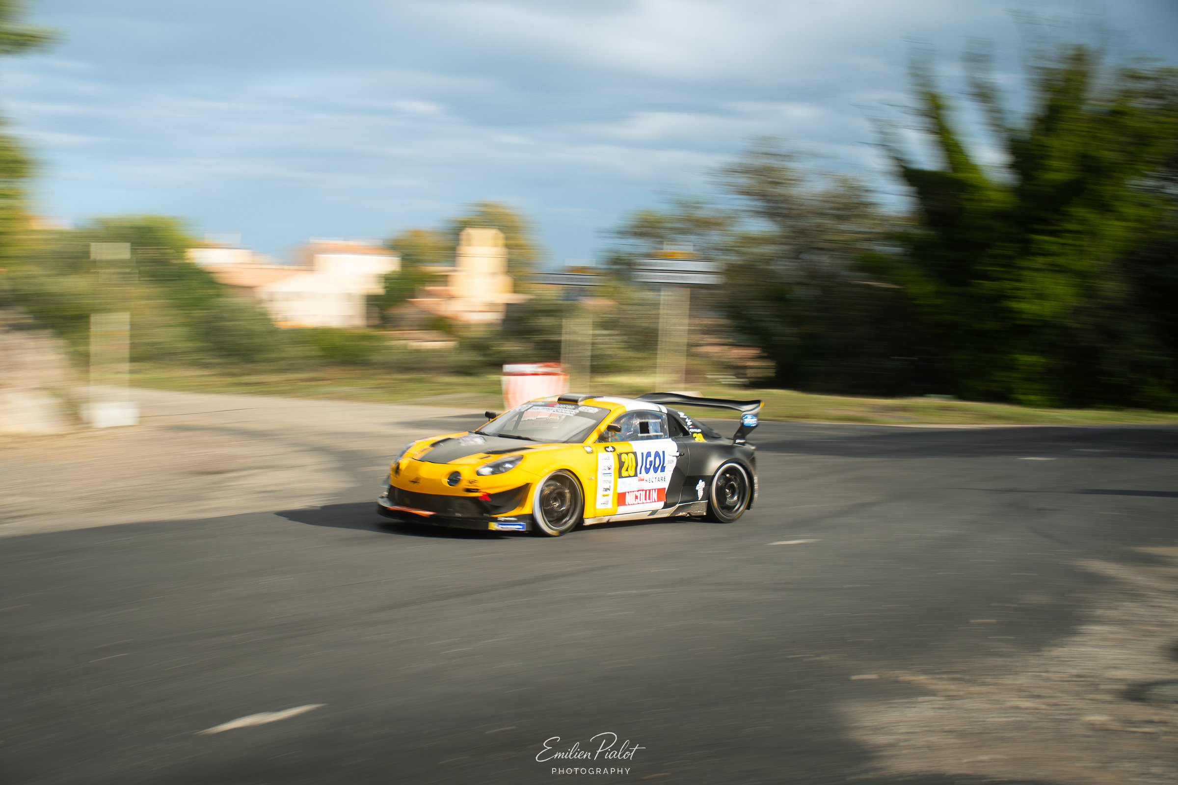 Voiture de rallye jaune et noire sur une route de prairie dans les Cévennes