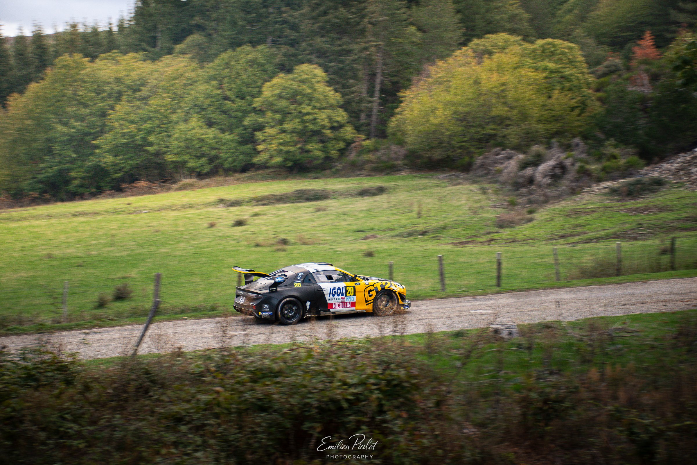 Voiture de rallye blanche de nuit au bord du ravin, public massé derrière