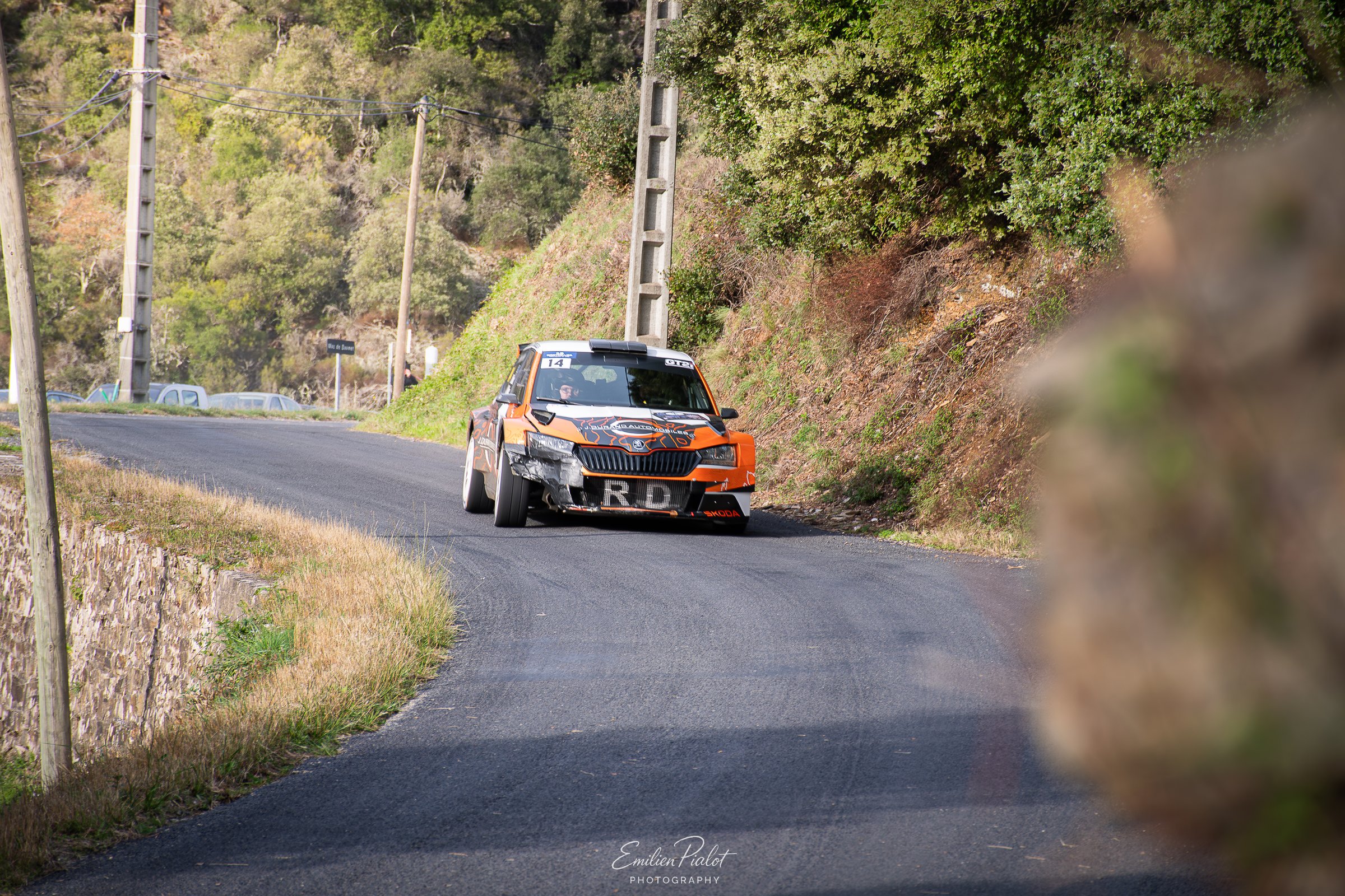 Voiture de rallye orange en sortie de virage sur route de montagne