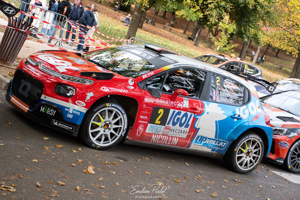 Peugeot 206 blanche sur chemin bordé d'arbres dorés