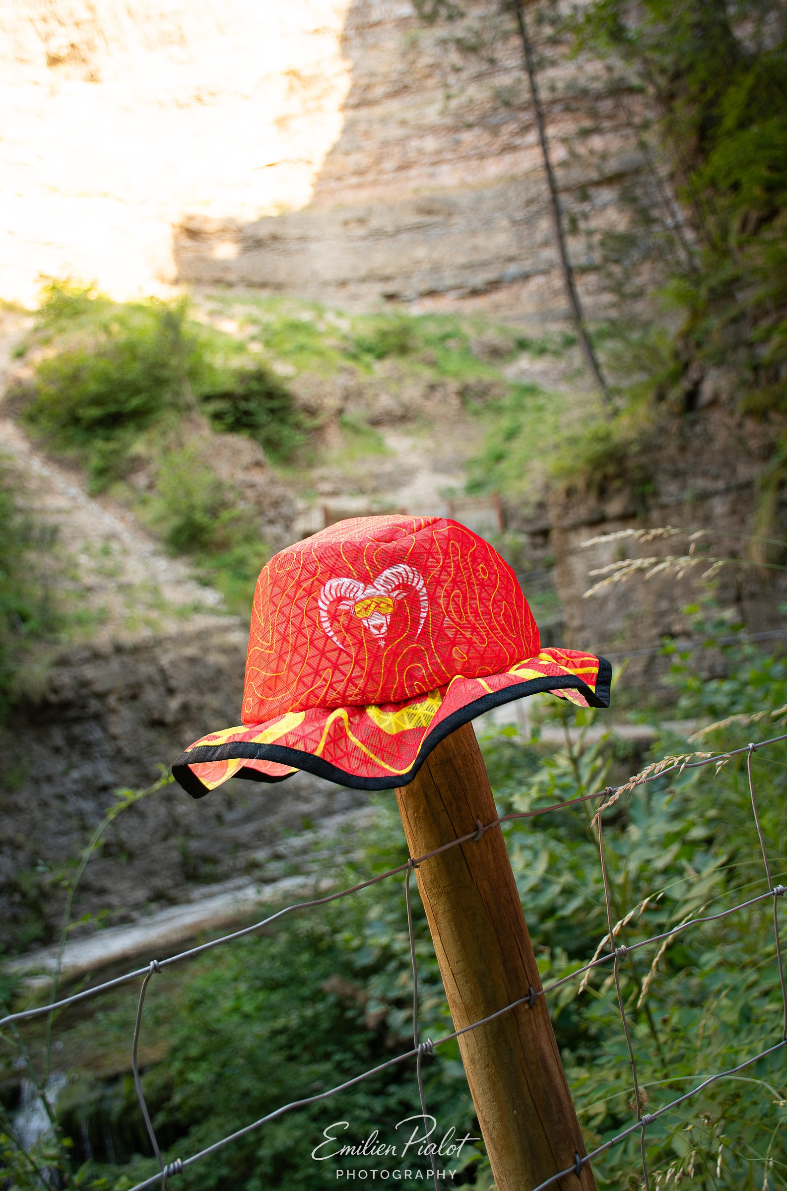 Casquette orange Muflon posée sur un piquet en bois, fond canyon