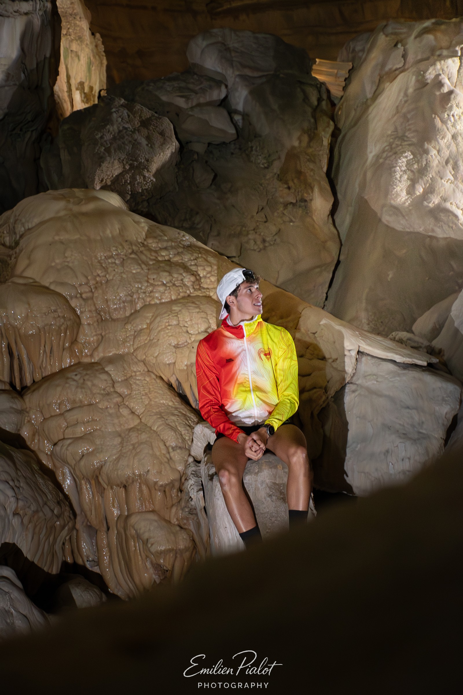 Séance Muflon en grotte, assis sur un rocher, veste jaune