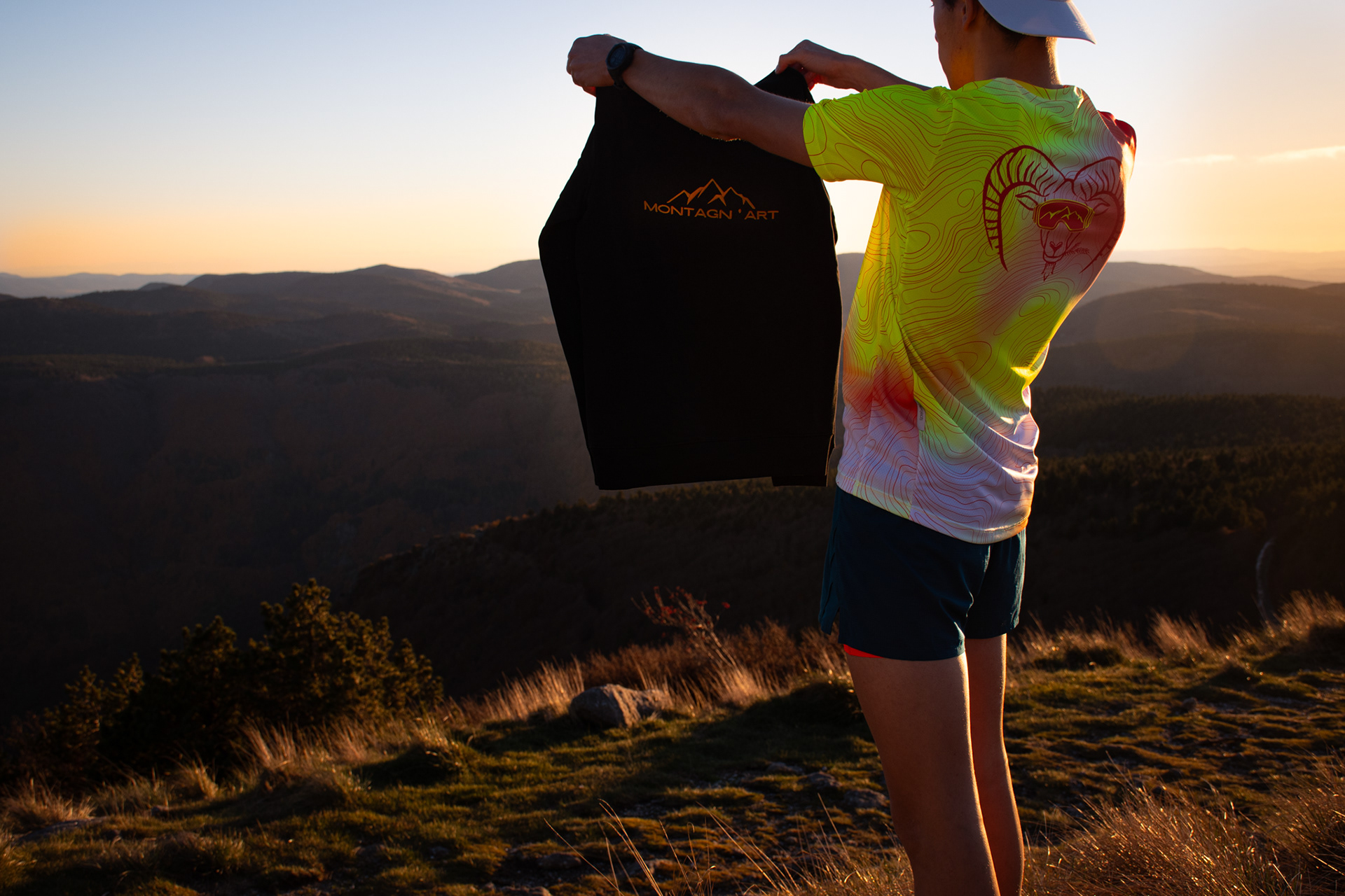 Modèle présentant un sweat Muflon by Montagn'Art face au coucher de soleil en montagne